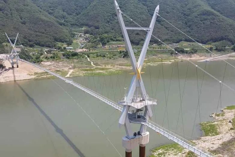 보현산댐 저수지를 가로지르는 출렁다리 전체와 X자 주탑 두 개 항공 사진