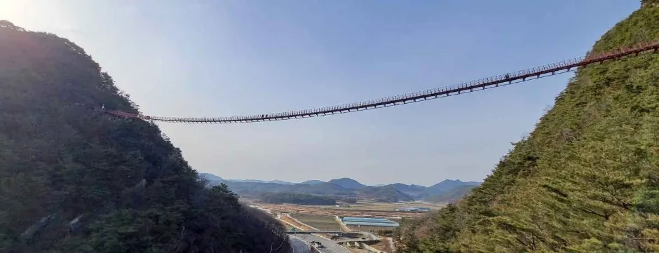 순창 채계산의 두 봉우리를 잇는 출렁다리와 그 아래 국도와 들판