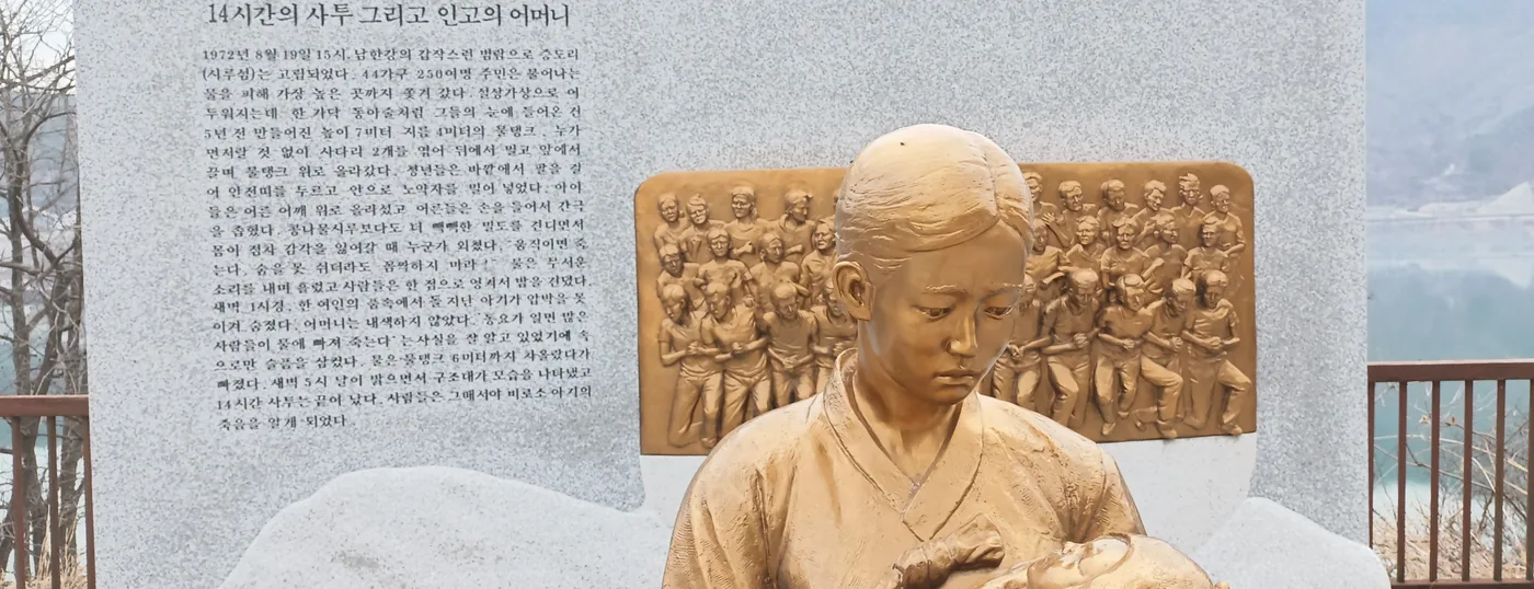 시루섬의 기적이라고 새긴 화강암 기념비와 아기를 안은 어머니 청동상, 주민들을 새긴 부조판