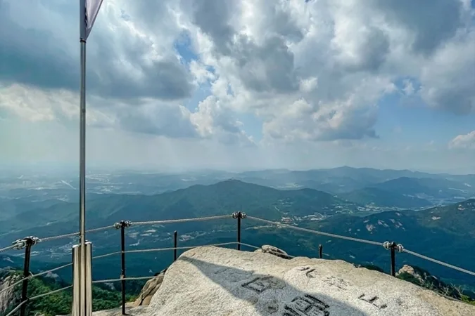Korean flag and the carved summit rock at the top of Baegundae, Bukhansan