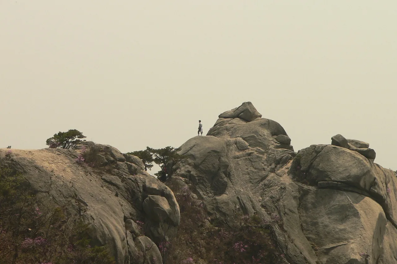 A hiker standing on a granite ridge of Bukhansan in spring